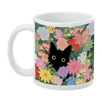 Черна котка се крие в пролетни цветя бяла халба